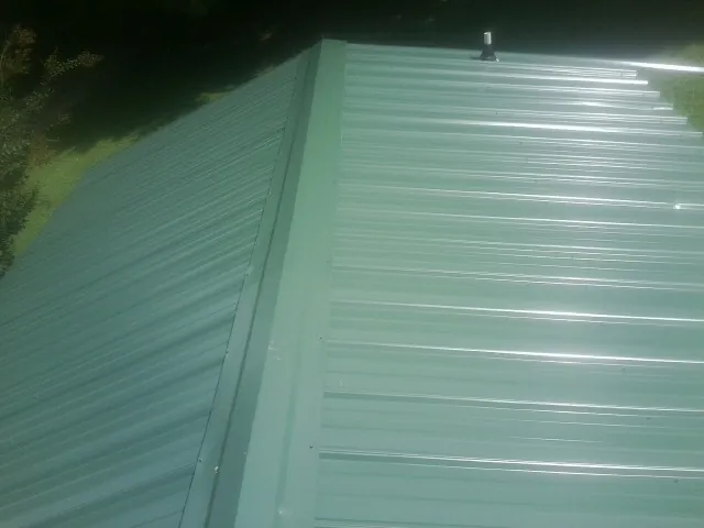 New green metal panels meeting at the ridge of a roof — Flat Roof Repair work by our crew in Seaboard