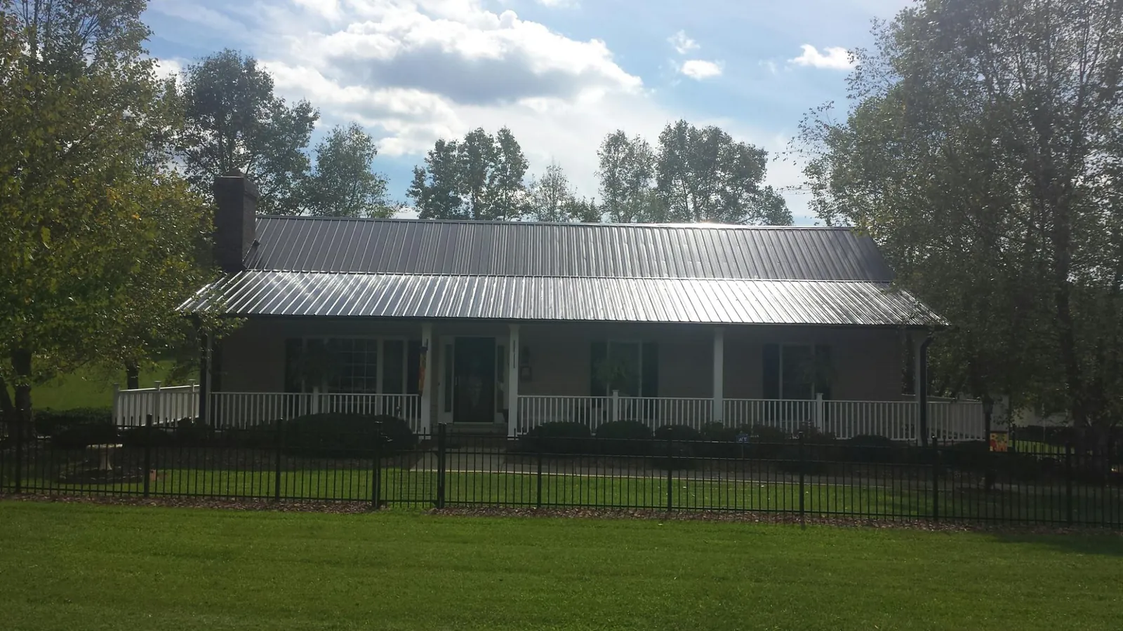 Gray metal roof on a brick ranch with a full width front porch — Gutter Guard Installation work by our crew in Seaboard
