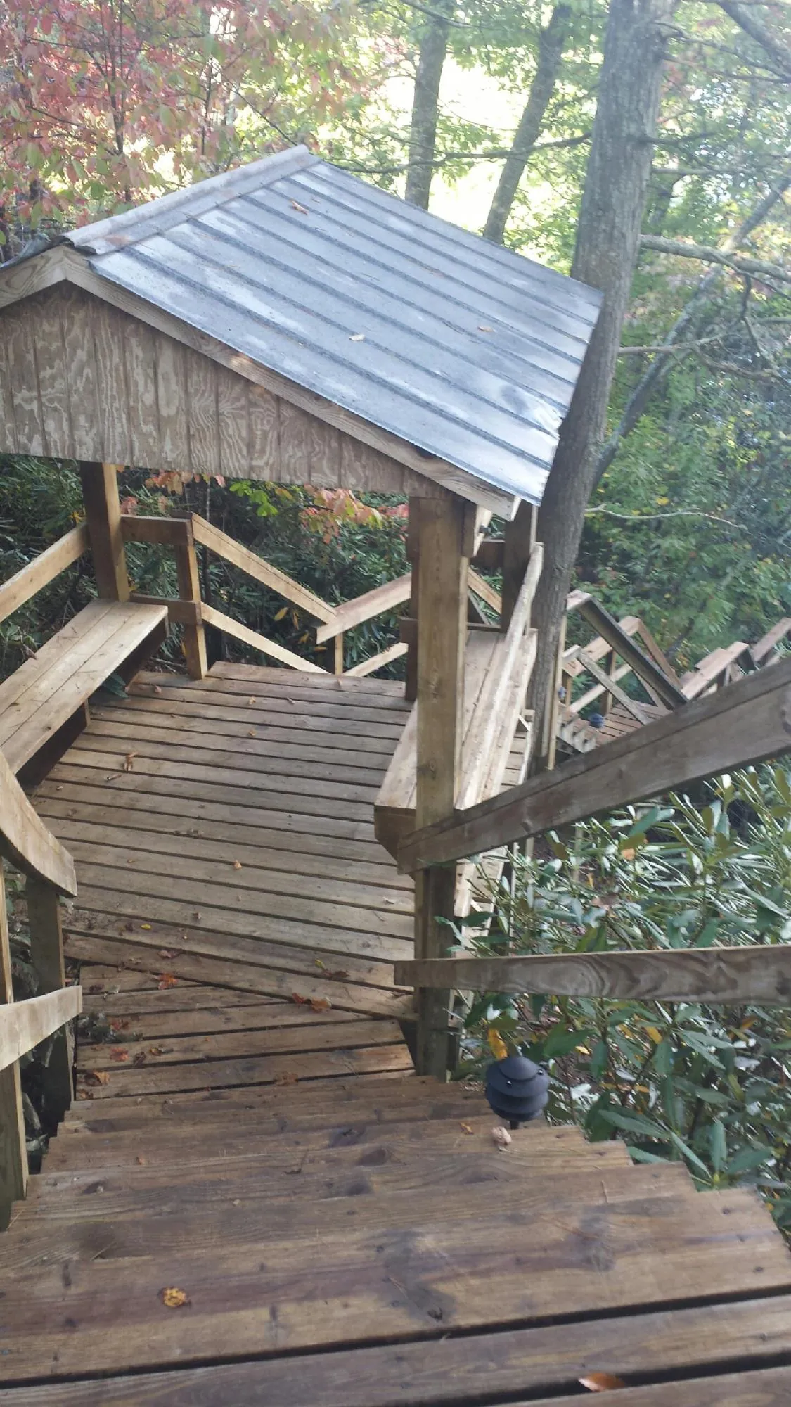 Metal roofed shelter over wooden steps on a wooded walkway — Skylight Repair & Installation work by our crew in Seaboard