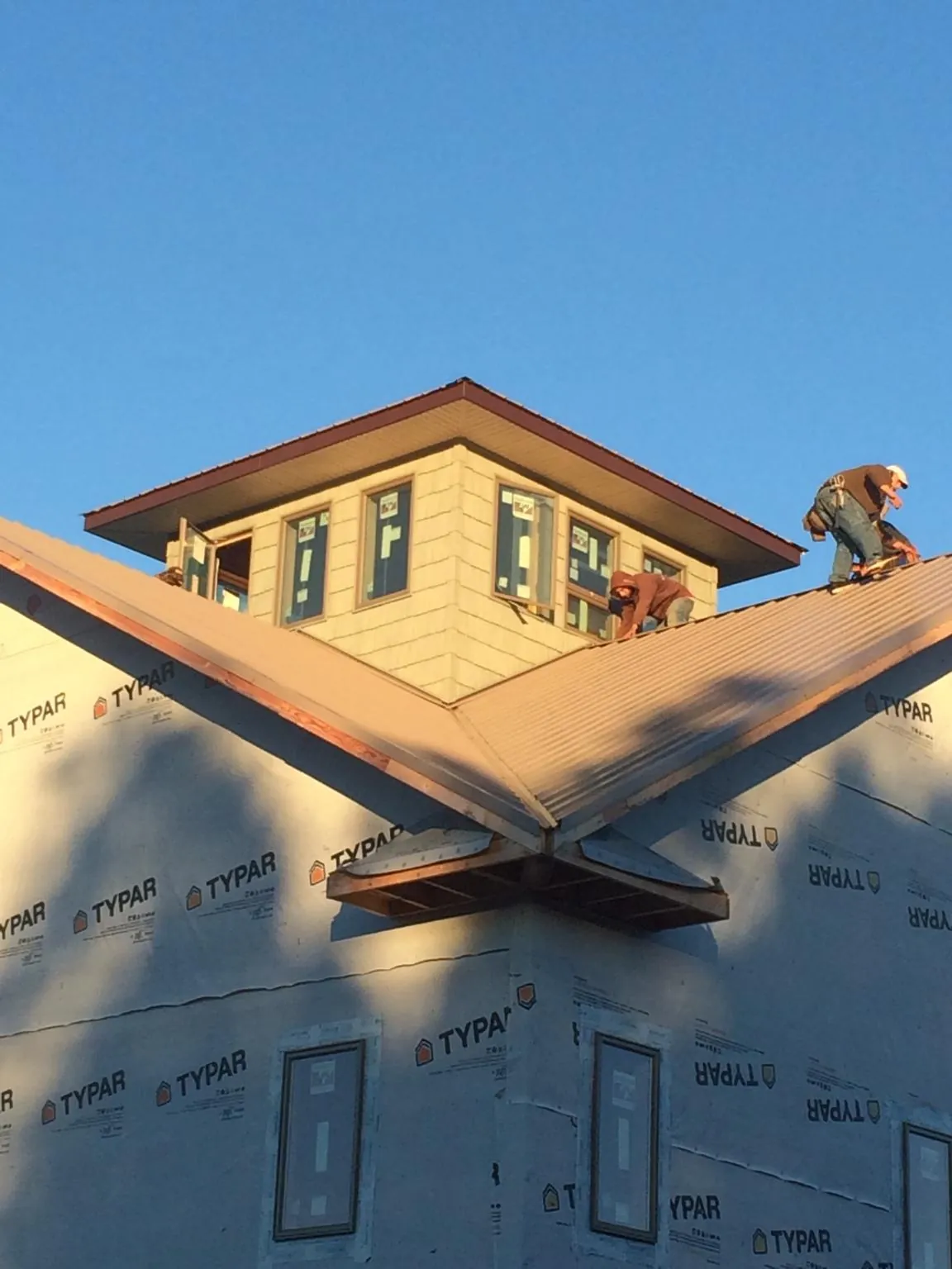 Roofers working around a rooftop cupola on a new metal roof at sunset — Roof Waterproofing in Seaboard by Roofing Brothers